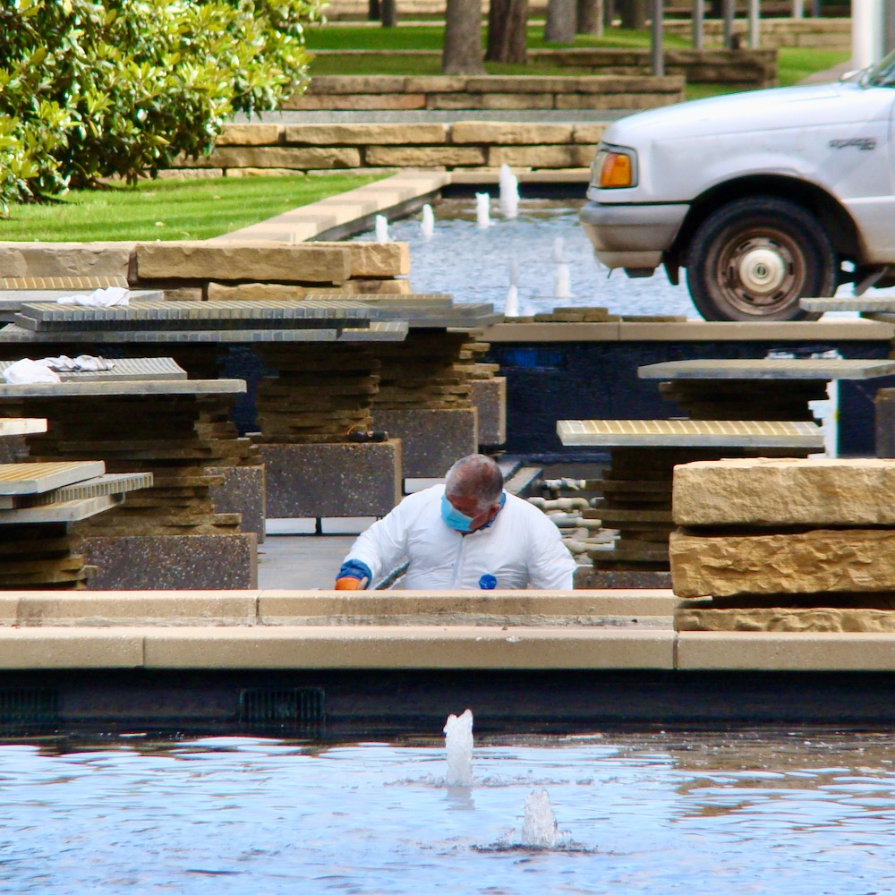 A facilities worker wearing personal protective equipment performs seasonal maintenance on one of the University’s reflecting pools.