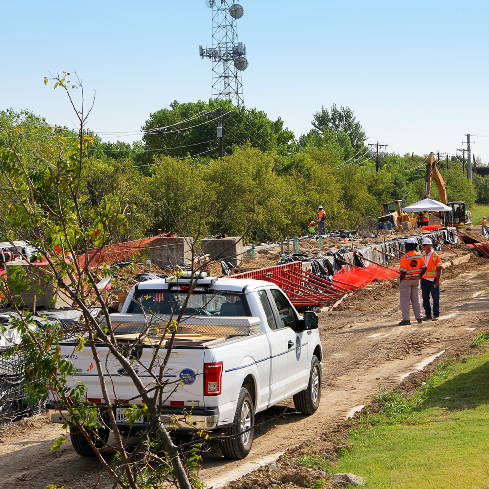 The foundation for an elevated concrete platform takes shape within a set of molds in the middle of a dirt track carved out of a wooded area.