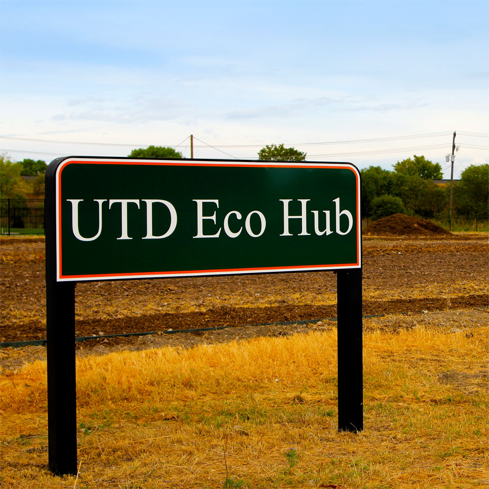 A sign reading “UTD Eco Hub” in front of an open field.