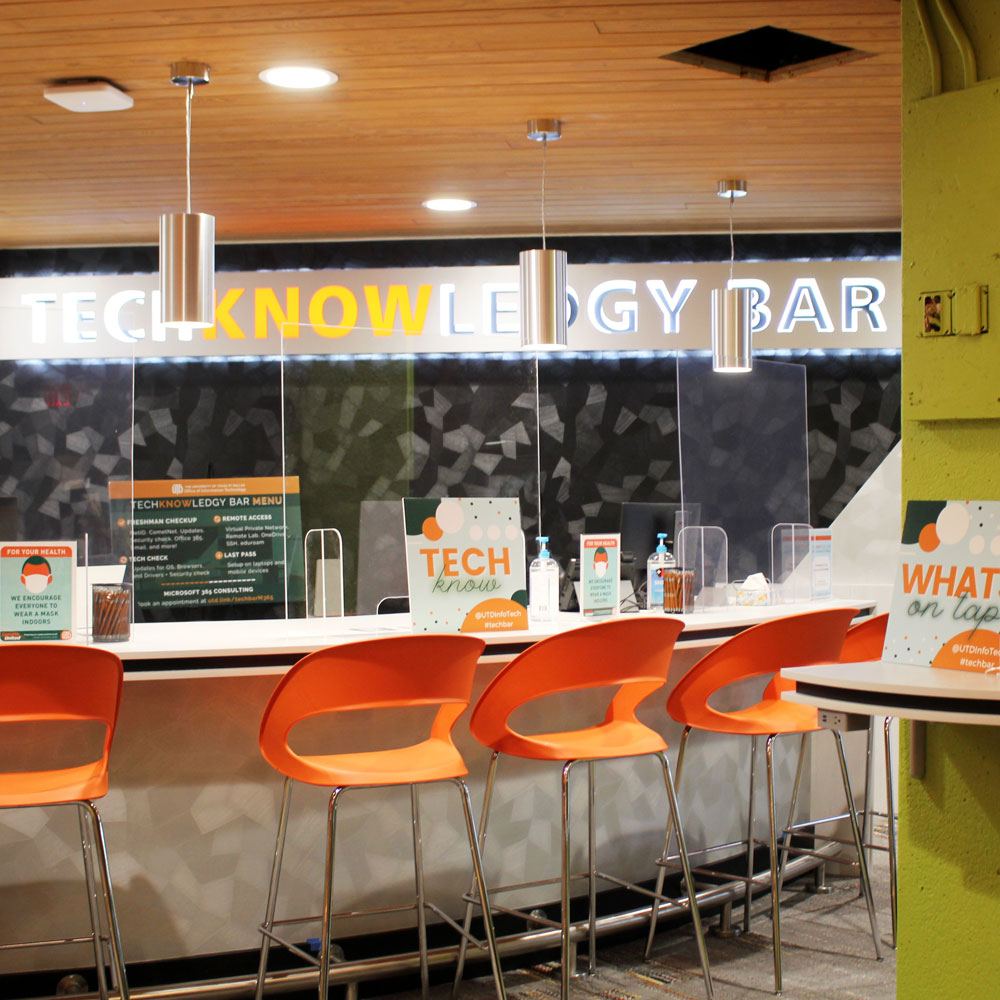 An industrial-style counter and chairs with a plastic, all done in shades of silver and black with pops of orange and green.