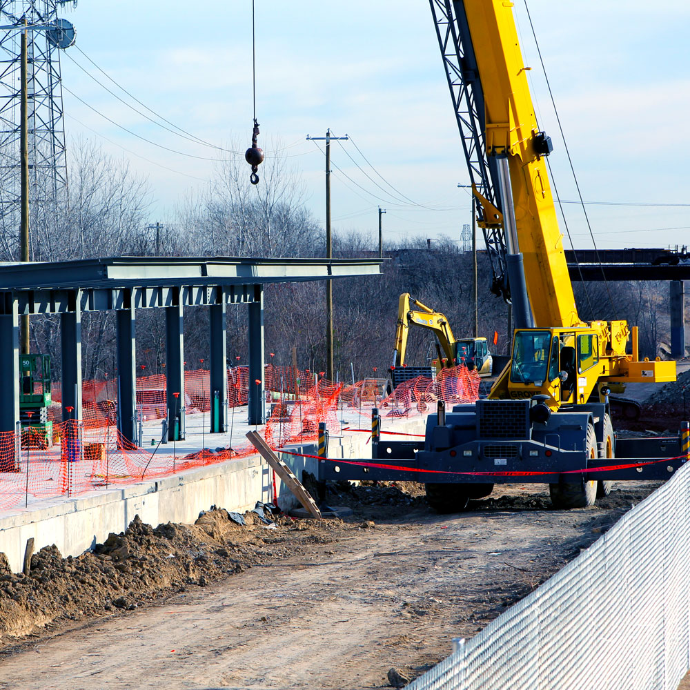 A crane working near the steel framework of a partially-constructed train platform.