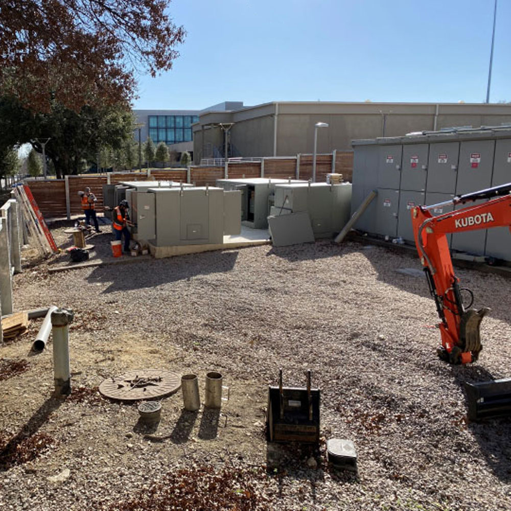 Workers install electrical equipment between buildings.