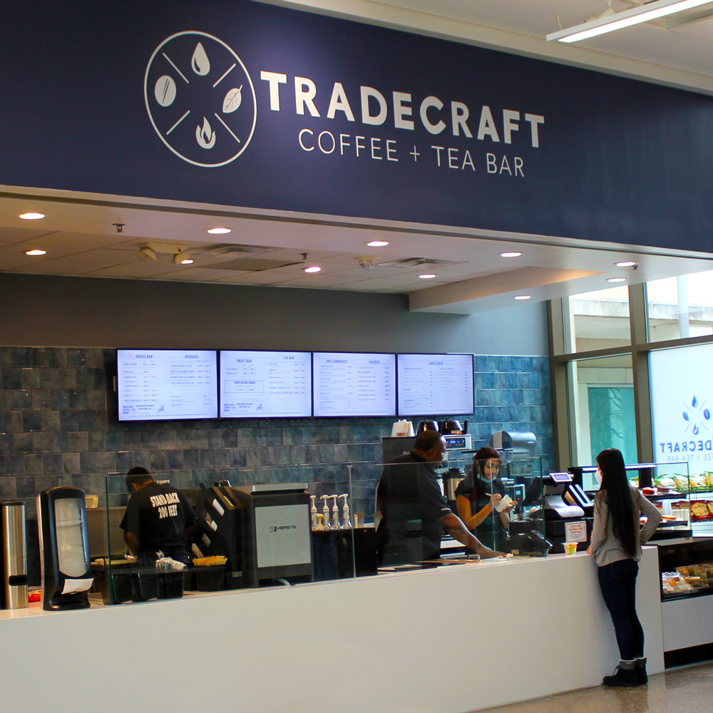 A student ordering from a counter which reads “Tradecraft Coffee and Tee Bar”