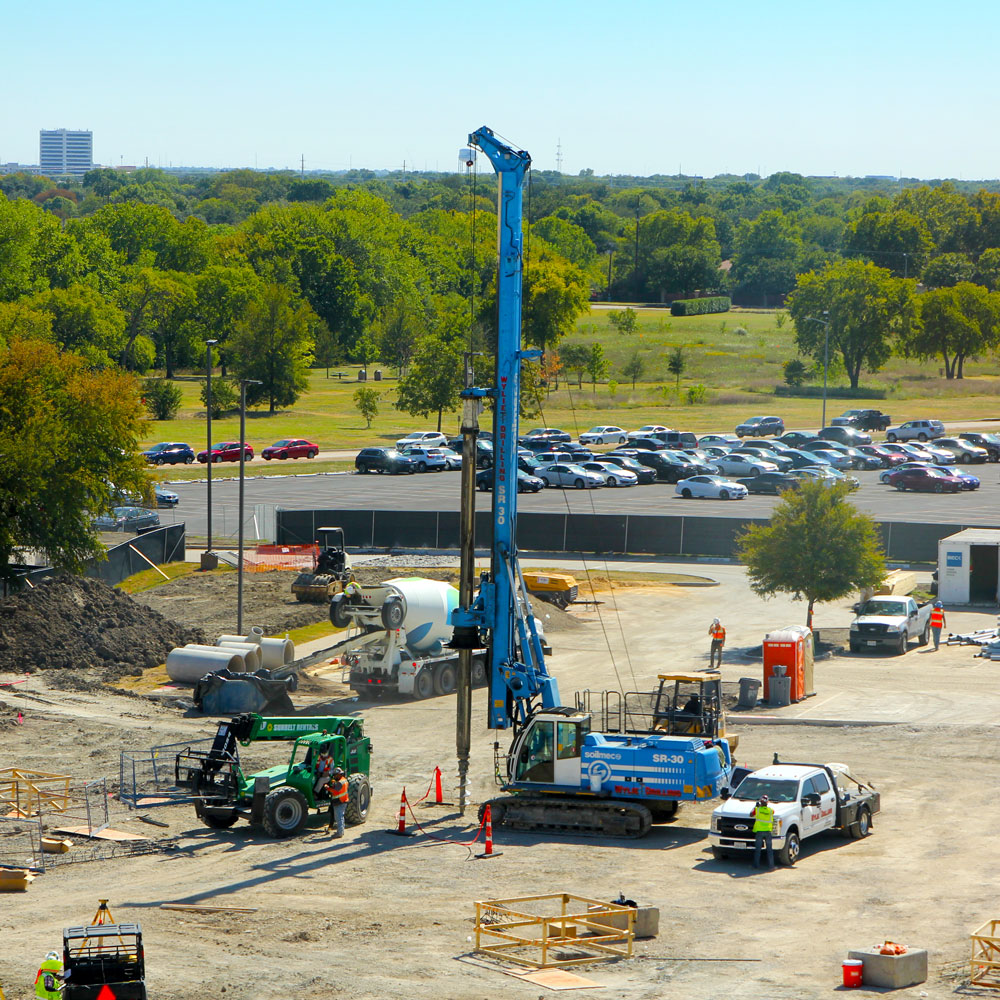 A large piece of construction equipment drills a hole in the dirt.