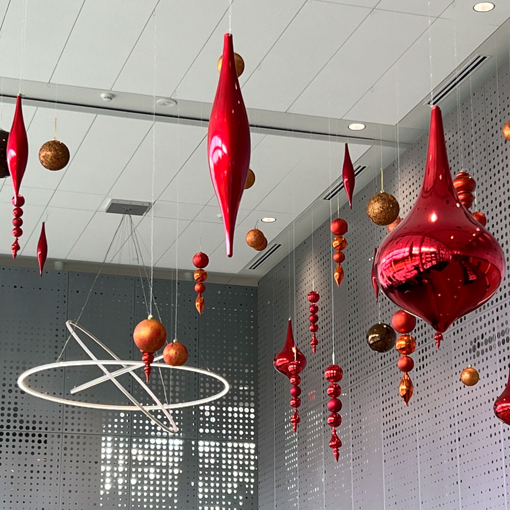 Oversized red ornaments hang suspended from a ceiling, surrounded by perforated metal walls.