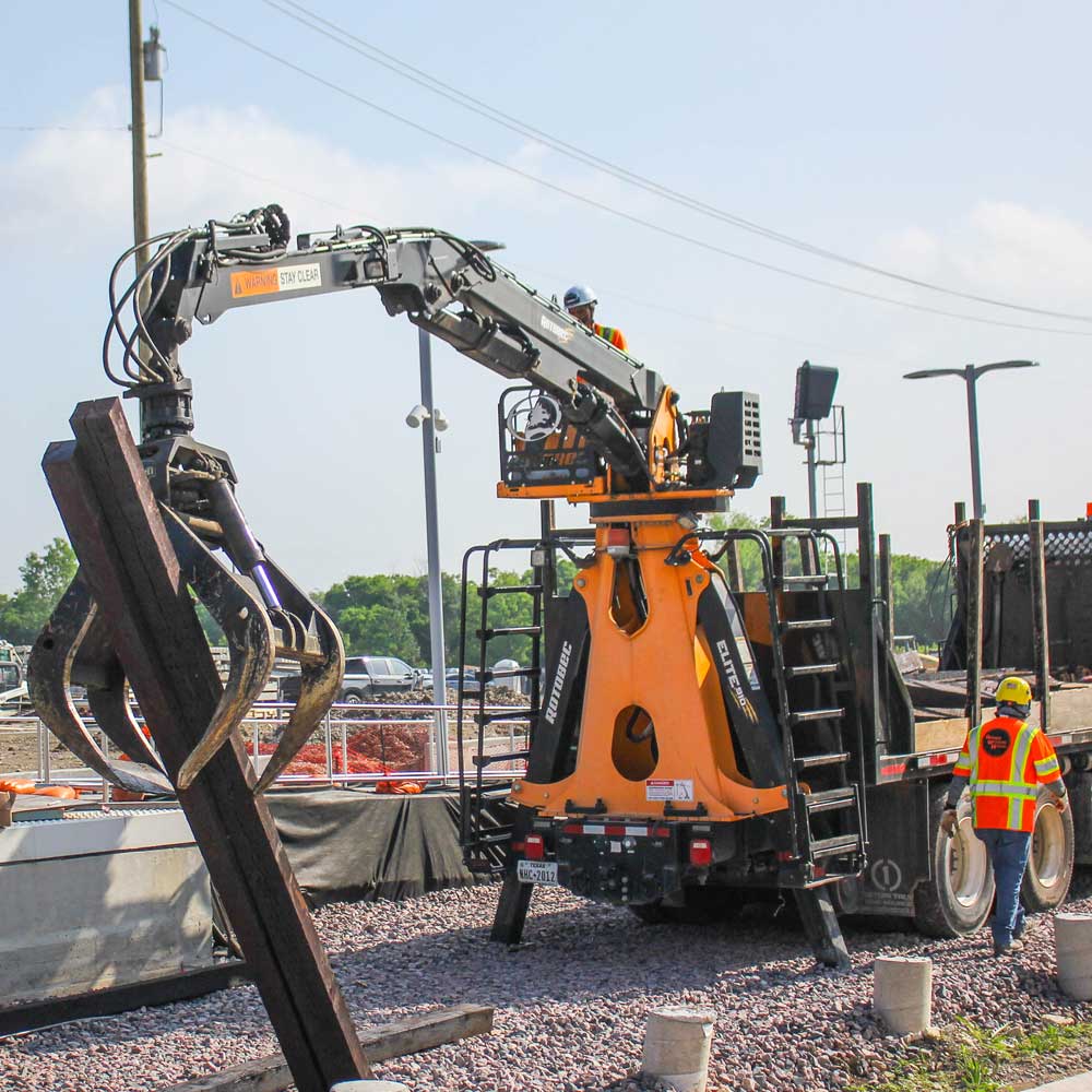 A piece of construction machinery lays down railroad tracks with a massive claw.