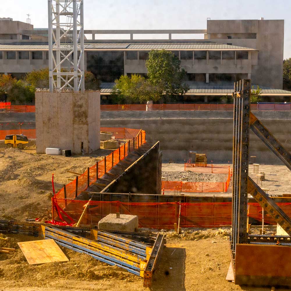 A construction site with a deep pit containing the bases of columns.