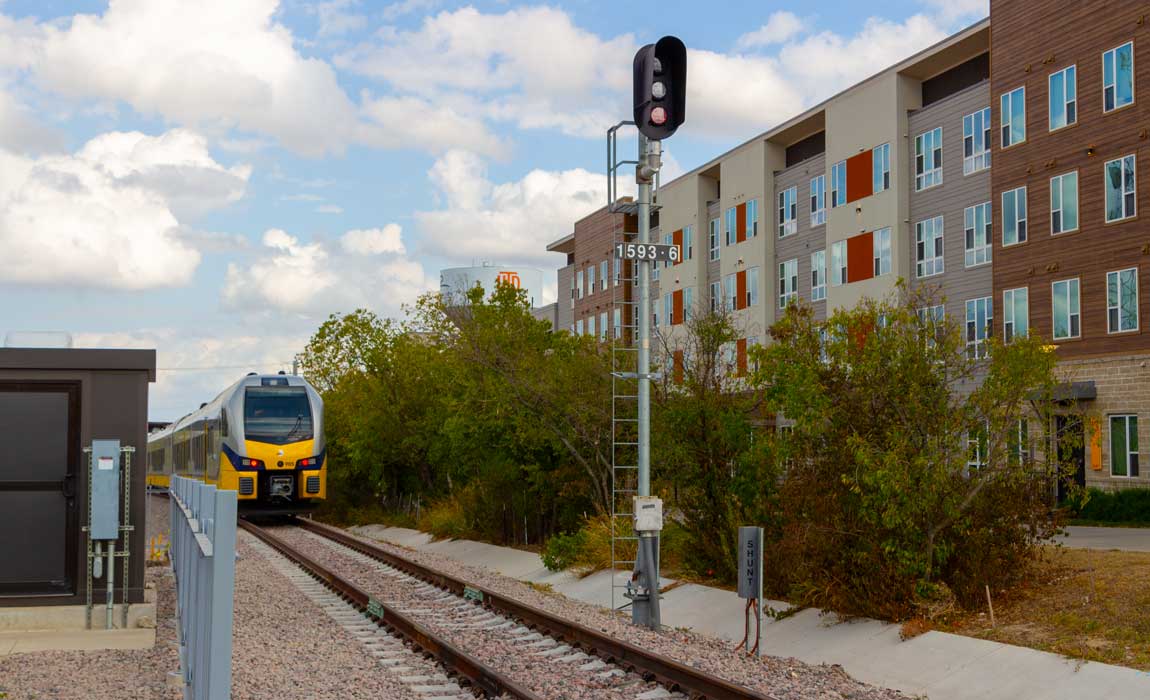 A DART Silver Line train passes by Northside at UT Dallas on its way into UTD Station.