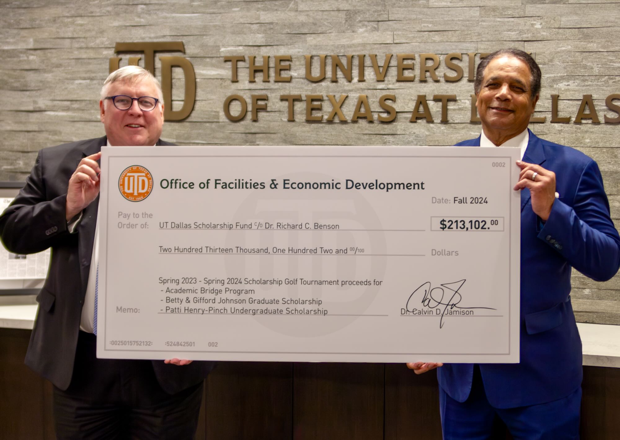 Two men hold a large check between them.