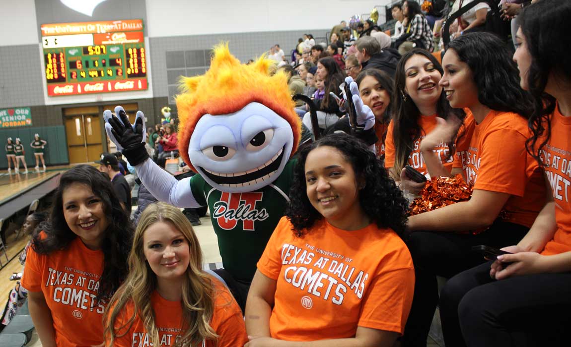 Community Appreciation Day. School mascot TEMOC cheers on the Comets basketball team surrounded by fans in the bleechers.